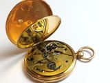 a gold pocket watch sitting on a white surface