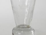 un verre transparent à fond plat posé sur une surface blanche