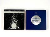 deux livres posés sur une surface blanche, l'un avec une couverture bleue et l'autre avec une couverture en noir et blanc