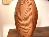 un vase marron posé sur une table en bois, avec un miroir en arrière-plan