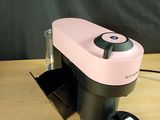 pink and black coffee maker sitting on top of a wooden table