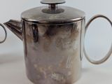 a silver teapot with a handle on a white table