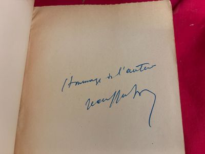 un livre ouvert, portant une signature manuscrite, posé sur un tissu rouge