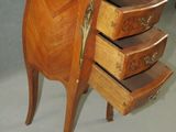a small wooden table with three drawers and a marble top