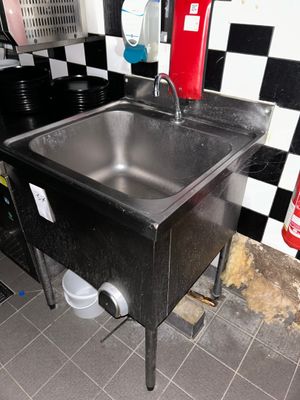 un évier dans un coin d'une cuisine aux murs à carreaux noirs et blancs