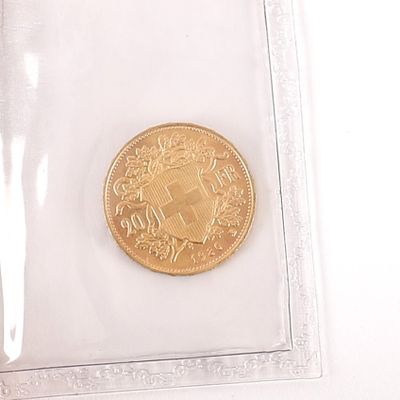 une pièce d'or dans un sachet en plastique transparent posé sur une surface blanche