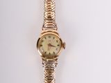 une montre-bracelet en or accrochée à un mur blanc