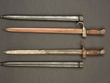 three old swords are lined up on a black surface