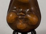 a small wooden sculpture of a laughing face on a stand