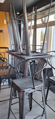 des tables et des chaises dans un restaurant, avec une grande baie vitrée en arrière-plan