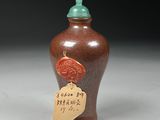 a brown vase with a green lid and a tag on it