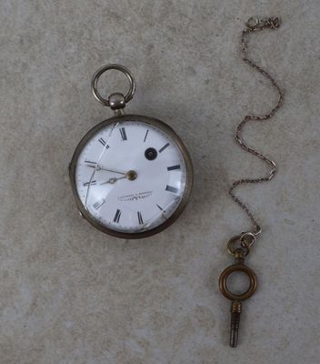 une montre de poche en argent à laquelle est attachée une clé