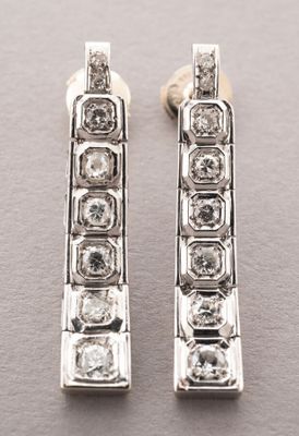 une paire de boucles d'oreilles en diamant posées sur une surface grise