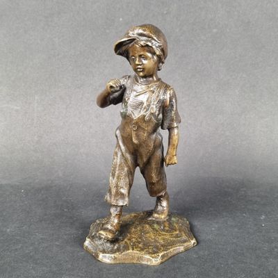 bronze figurine of a boy holding a bird on a rock