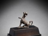 une figurine en bronze représentant un chien, posée sur un socle en bois
