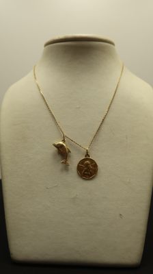 a close up of a necklace with a bird and a coin on a mannequin