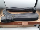 pair of black leather boots with buckles sitting on top of a cardboard box