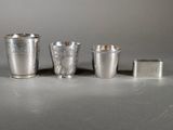 three silver cups and a lighter sitting on a table