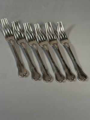 six fourchettes sont disposées en rangée sur une surface blanche