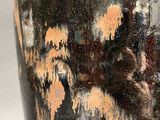 a black vase with yellow and brown designs on it
