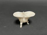 small white ceramic bowl with legs on a black surface