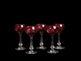 six verres à vin rouge sont alignés sur un fond noir