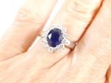 an image of a woman ' s hand holding a blue sapphire and diamond ring