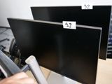 deux écrans d'ordinateur posés sur un bureau, avec des étiquettes de prix dessus