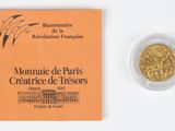 an image of a gold coin next to a booklet on a white surface