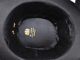 someone is holding a black hat with a gold emblem on it