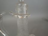 a clear glass pitcher with a handle on a table