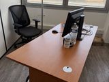a desk with a computer and a chair in the corner