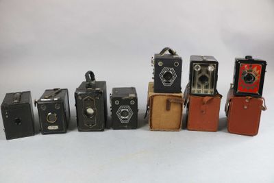 several old cameras are lined up in a row on a white surface