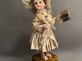 an old fashioned doll with a book and hat on top of a wooden block