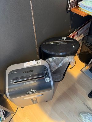a paper shredder sitting on the floor next to a trash can