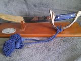 un couteau posé sur un support en bois orné d'un pompon bleu