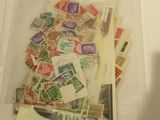 de nombreux timbres différents dans un sachet transparent posé sur une table