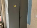 un réfrigérateur dans un coin d'une pièce, sur lequel est accrochée une pancarte