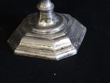 a silver plate with a candle on it on a black table