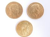 three different types of gold coins sitting on top of a white surface