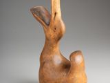 a brown sculpture of a rabbit sitting on top of a white surface