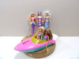 trois poupées Barbie dans un bateau avec une sirène et une queue de sirène