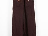 Le pantalon marron est suspendu à un cintre contre un mur blanc.