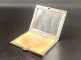 a small compact mirror sitting on a black surface
