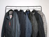 several jackets are hanging on a rack in a room