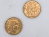two gold coins sitting next to each other on a white surface