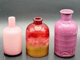 trois bouteilles en verre de couleurs différentes posées les unes à côté des autres