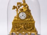 une horloge en or sous un dôme de verre sur une table