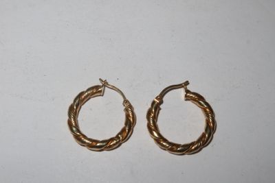deux paires de boucles d'oreilles en or sur fond blanc