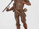 statue d'un homme tenant une faux, assis sur un rocher